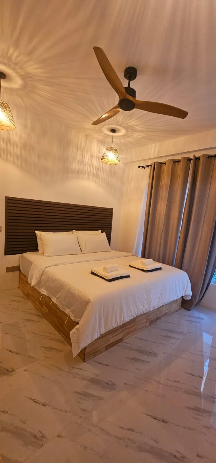 Guest room with double bed, curtains and ceiling fan at Ale Sara Guest House on Thoddoo, Maldives