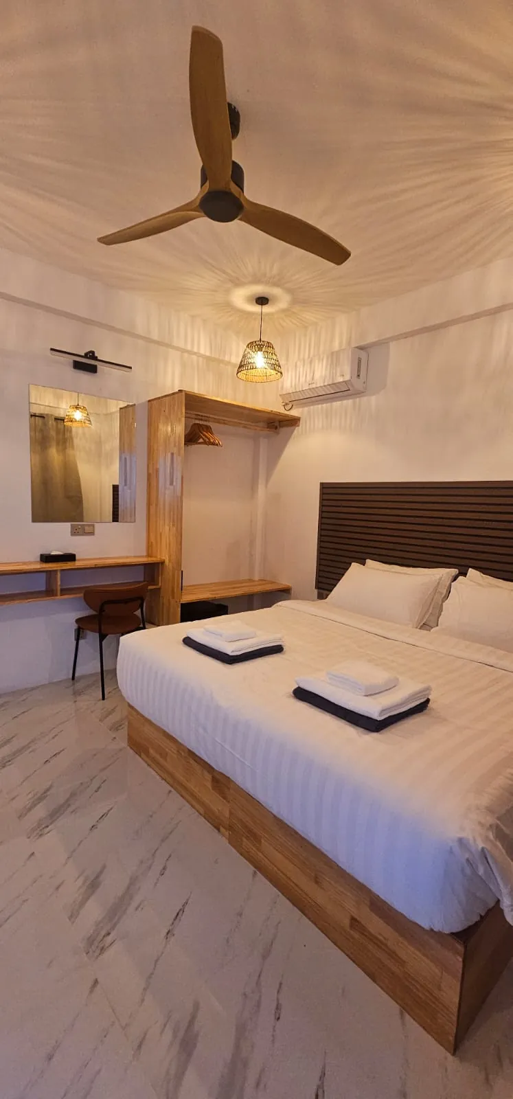 Guest room with wooden bed frame and ceiling fan at Ale Sara Guest House on Thoddoo, Maldives