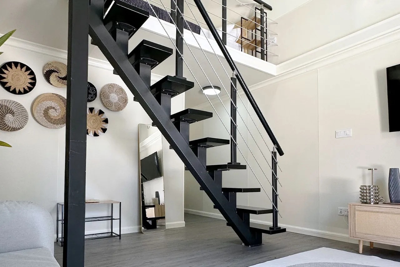 Villa living area with staircase to the loft bedroom at Ambra Maldives, Thoddoo