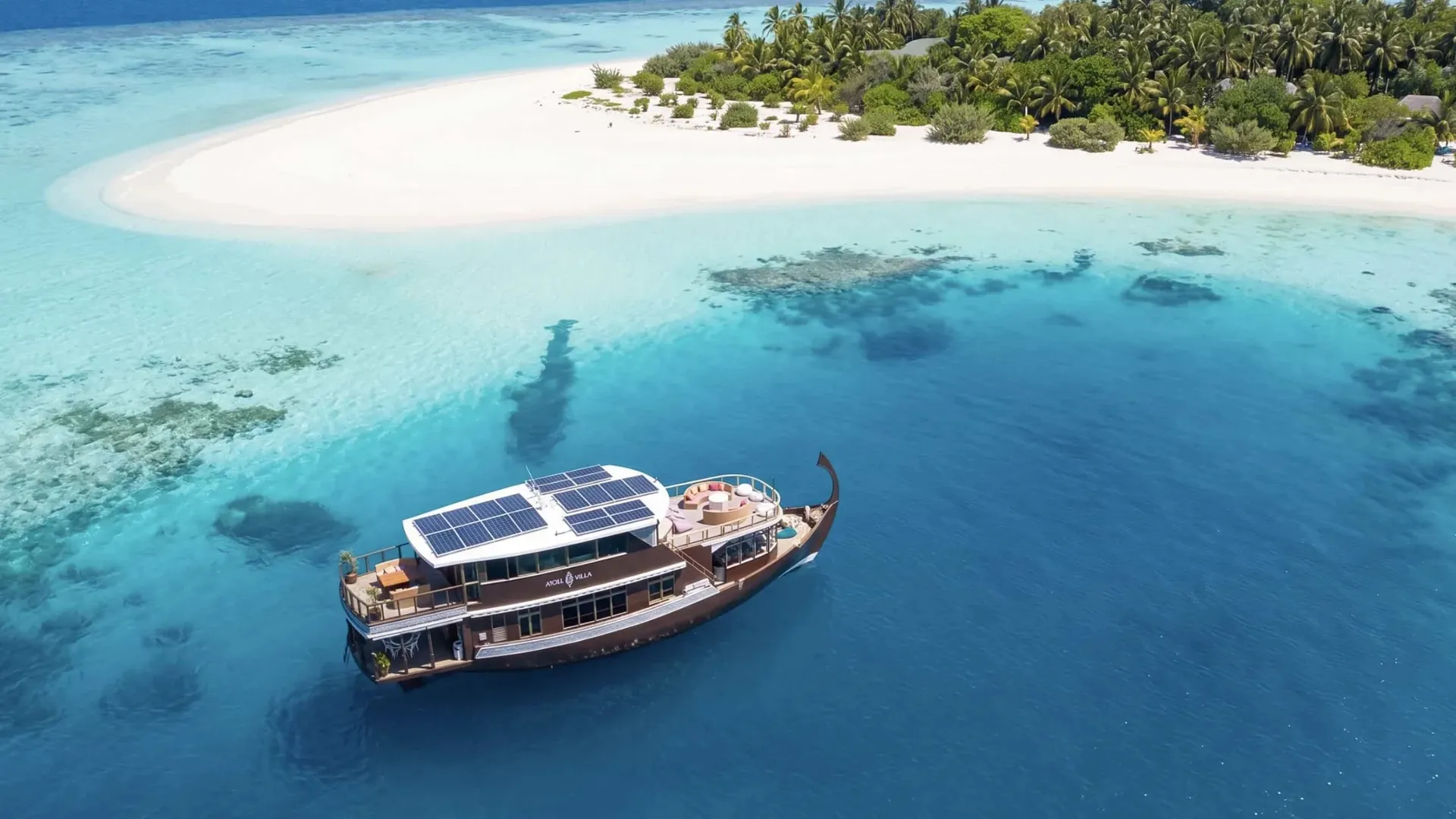 Atoll Villa private charter yacht cruising beside a white sandbank in the Maldives